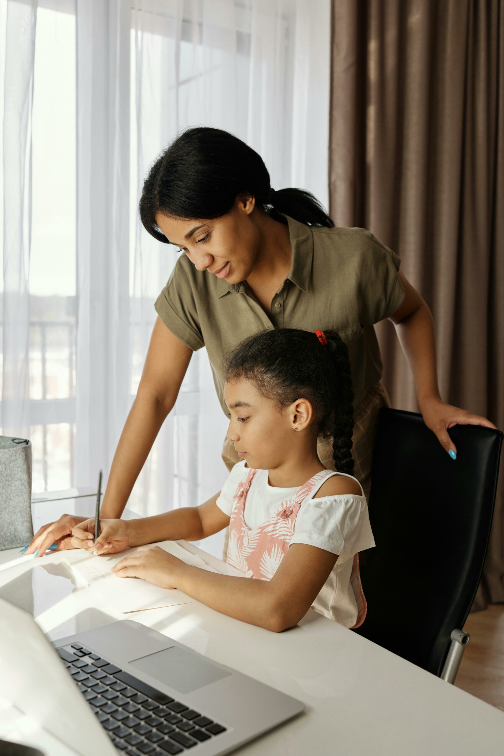 A nanny providing attentive homework assistance to a girl, exemplifying the professionalism, dedication, and safety focused childcare offered by Lifetime of Love Nannies