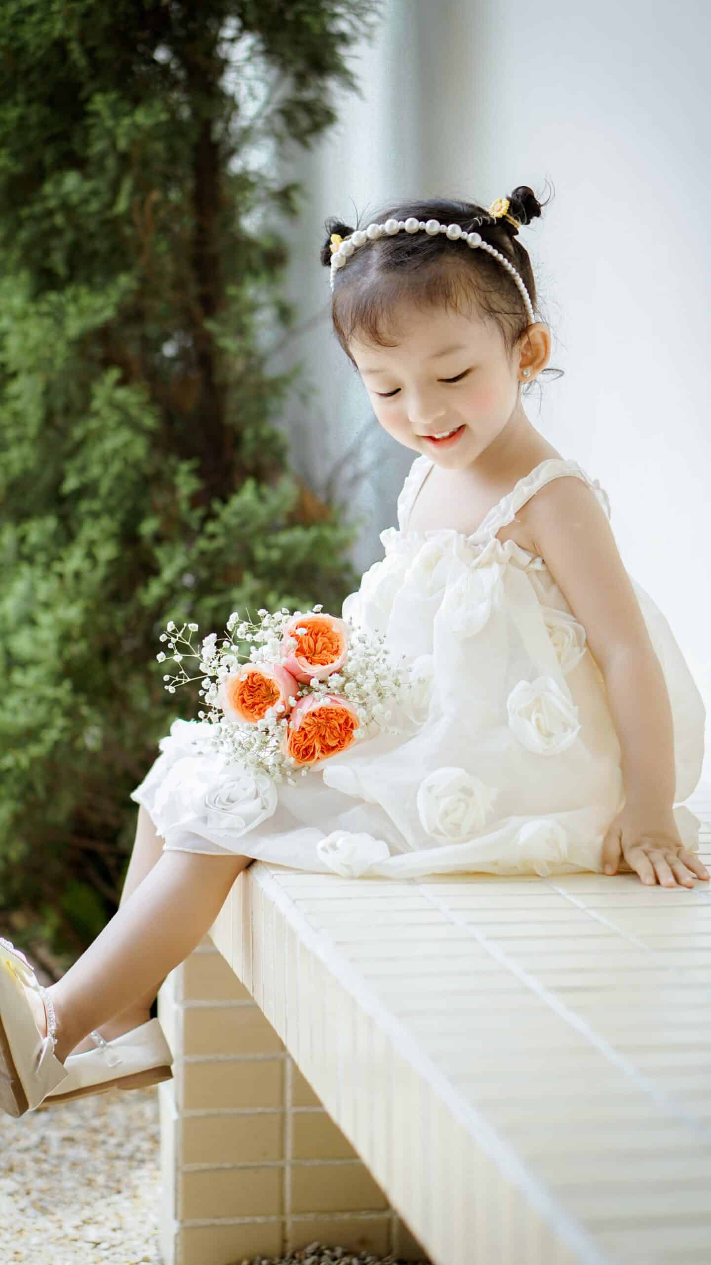 Adorable little girl joyfully holding a bouquet of flowers demonstrating the engaging and memorable experiences provided by Lifetime of Love Nannies scaled