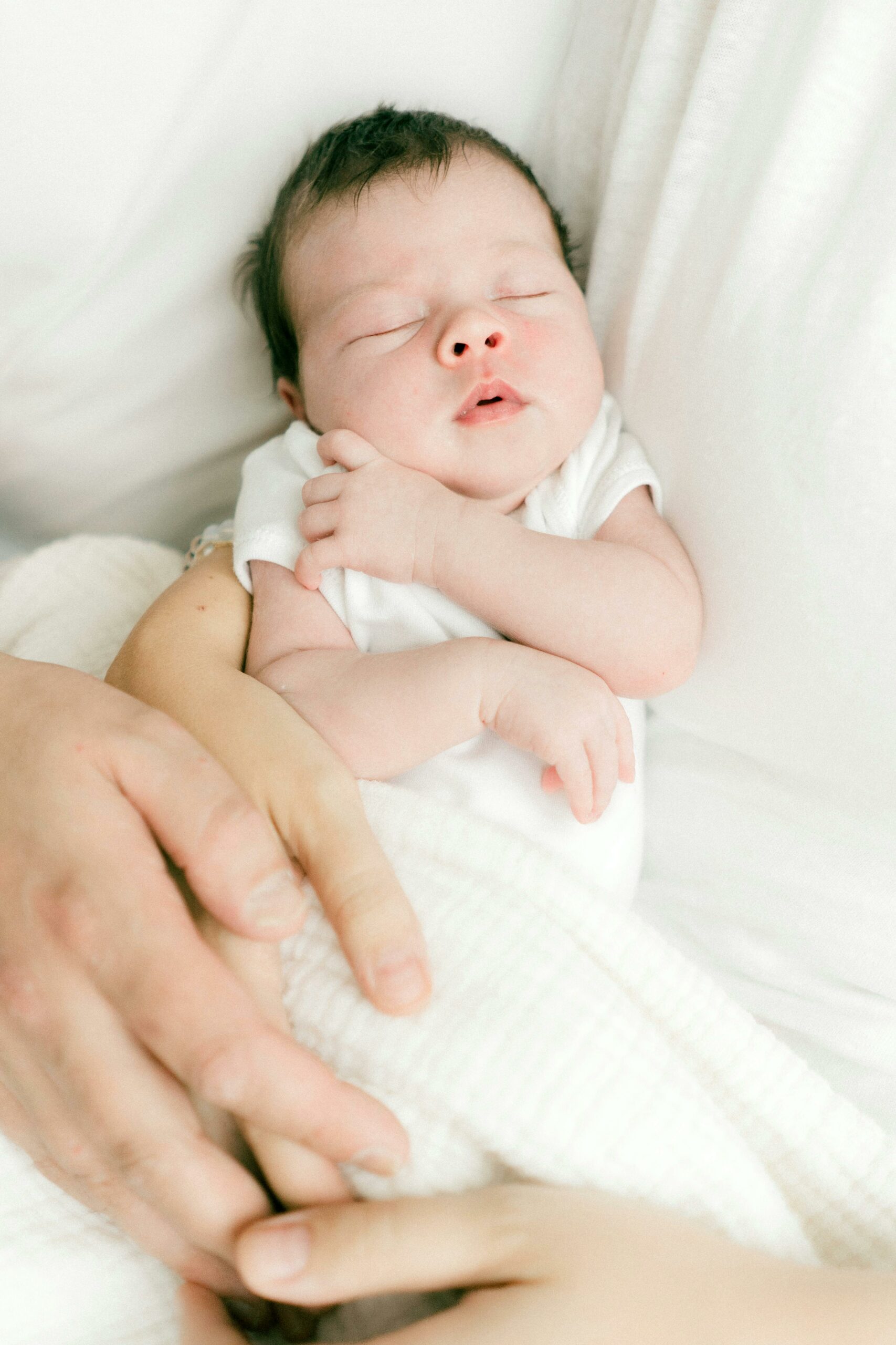 Closeup of a peaceful newborn baby cradled securely in the loving arms of its parents, illustrating the expert, supportive, and safe newborn care services provided