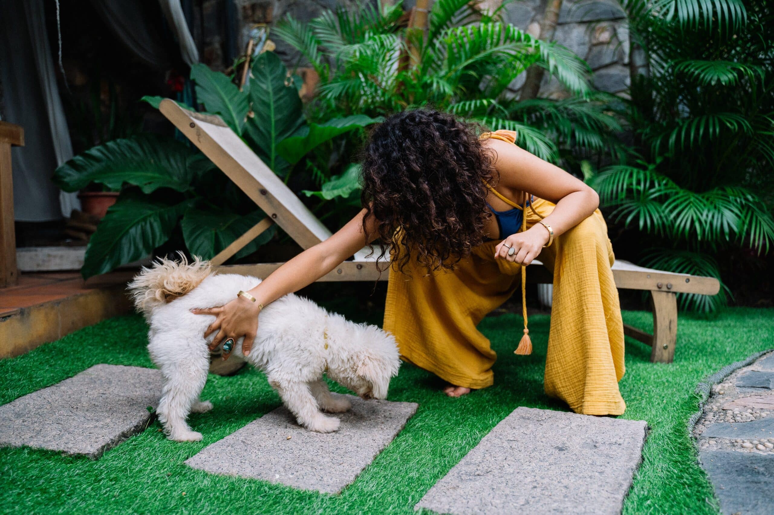 Pet sitter joyfully playing with a dog in a garden, exemplifying the dedicated, experienced, and safe pet care provided by Lifetime of Love Nannies