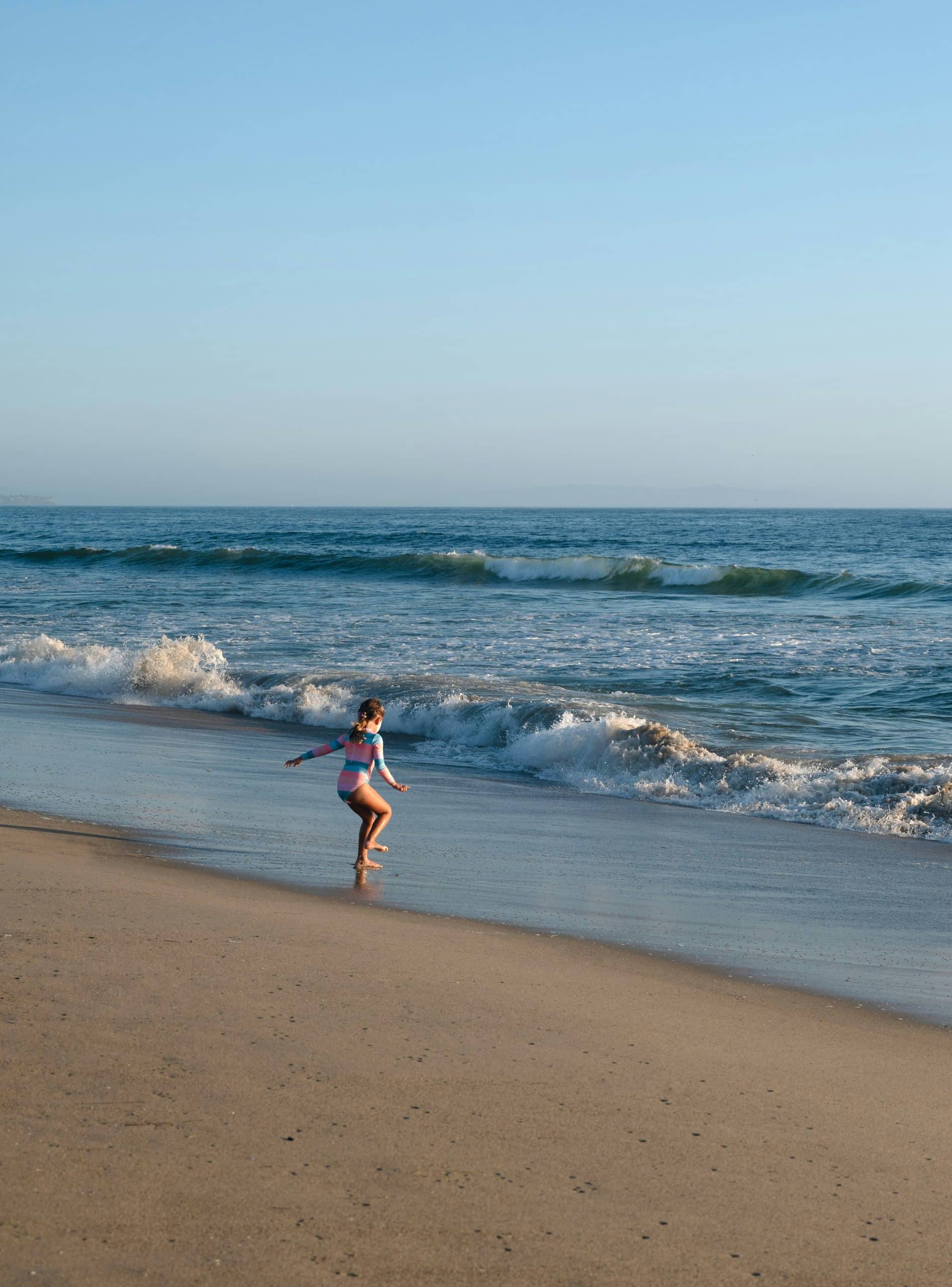 Child playing at the shoreline of a West Los Angeles beach with gentle waves in the background