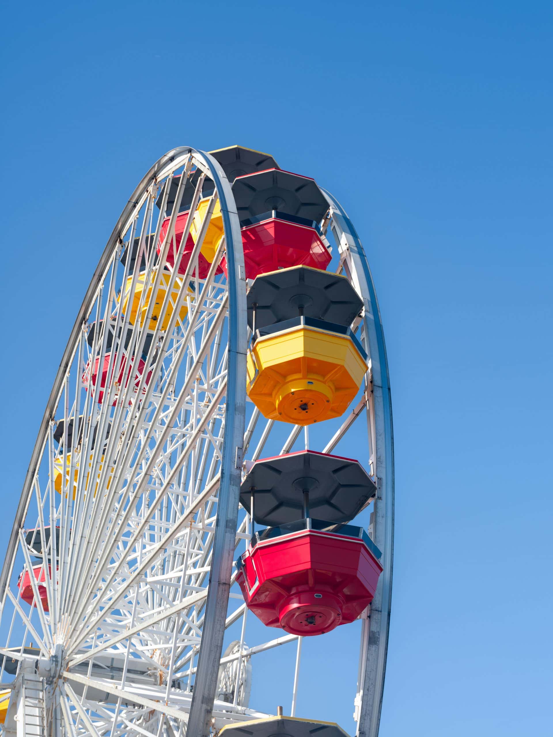 Ferris wheel at Santa Monica Pier with colorful gondolas against a clear blue sky