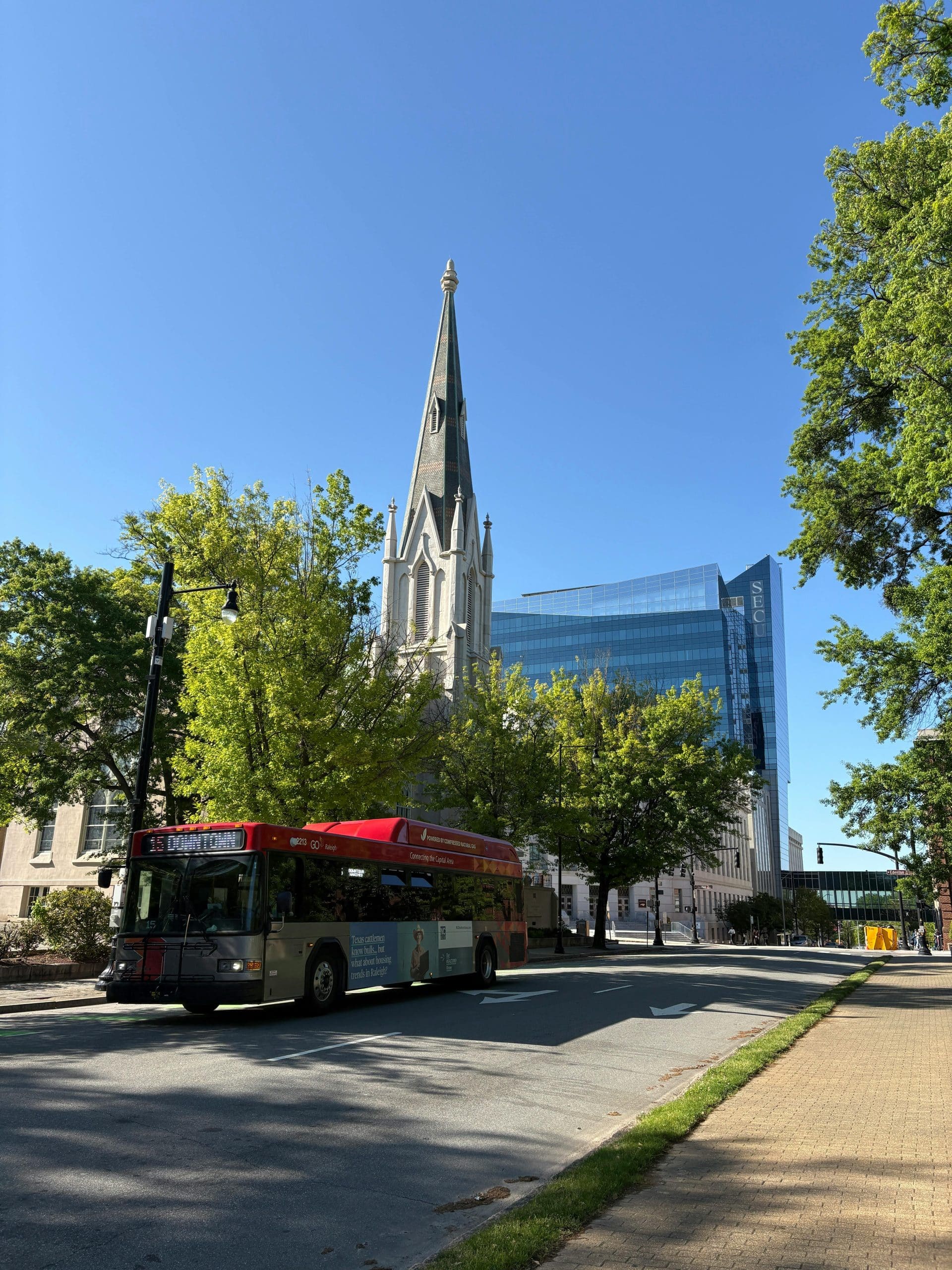 Raleigh city street with a GoRaleigh bus passing historic downtown architecture on a clear morning.