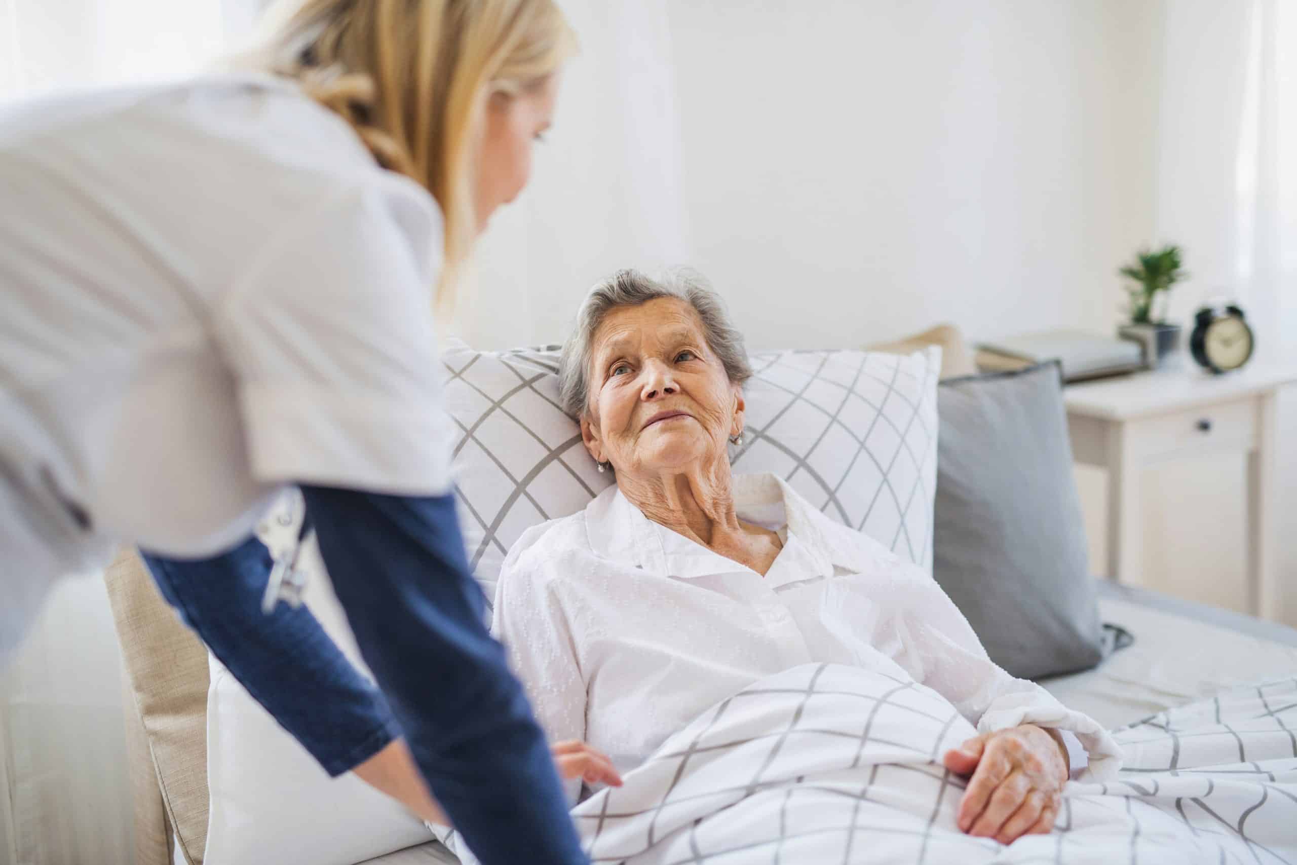 In home companion caregiver providing attentive support and conversation to an older adult resting comfortably at home
