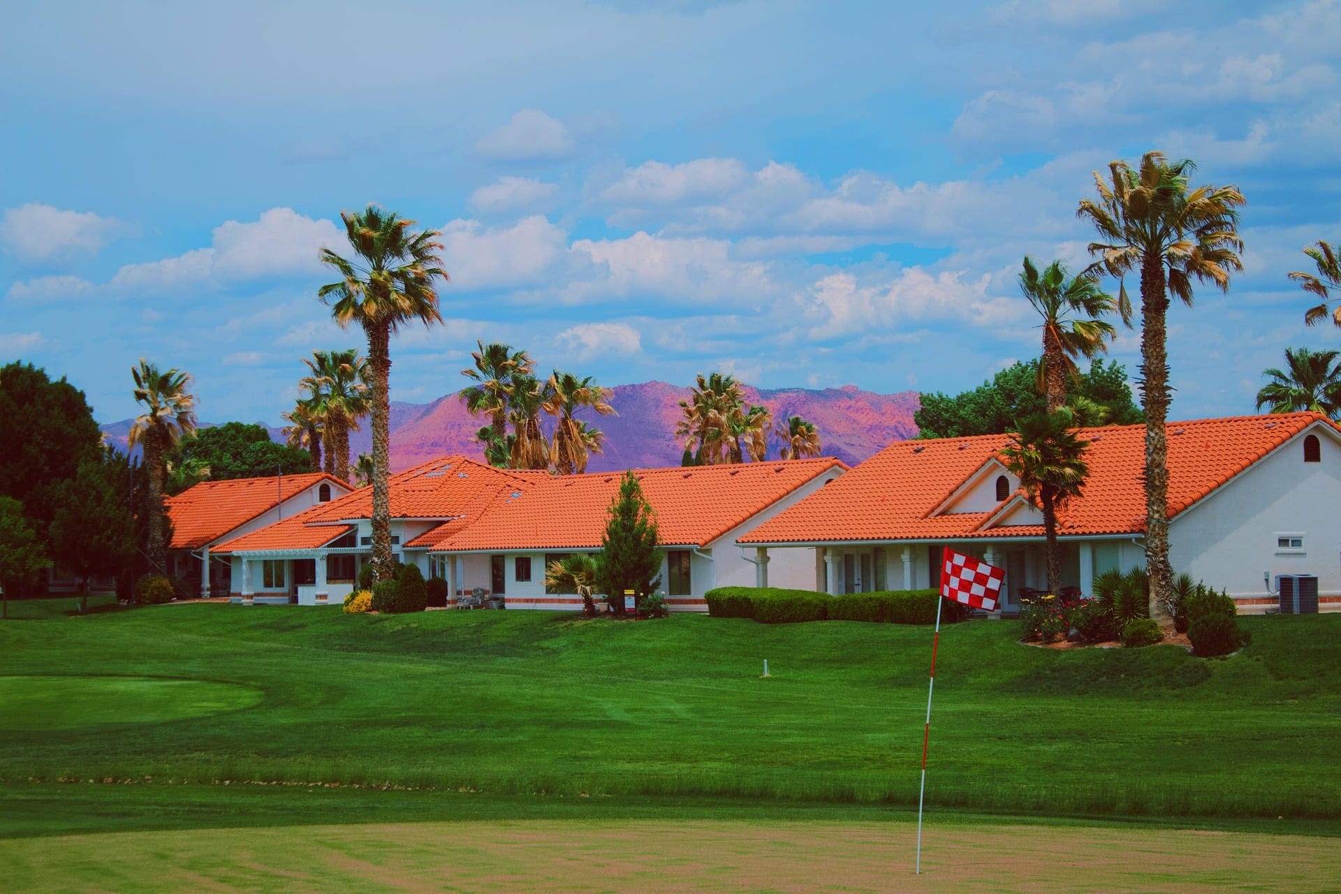 Suburban homes in southern Utah with palm trees and red tiled roofs against a mountain backdrop