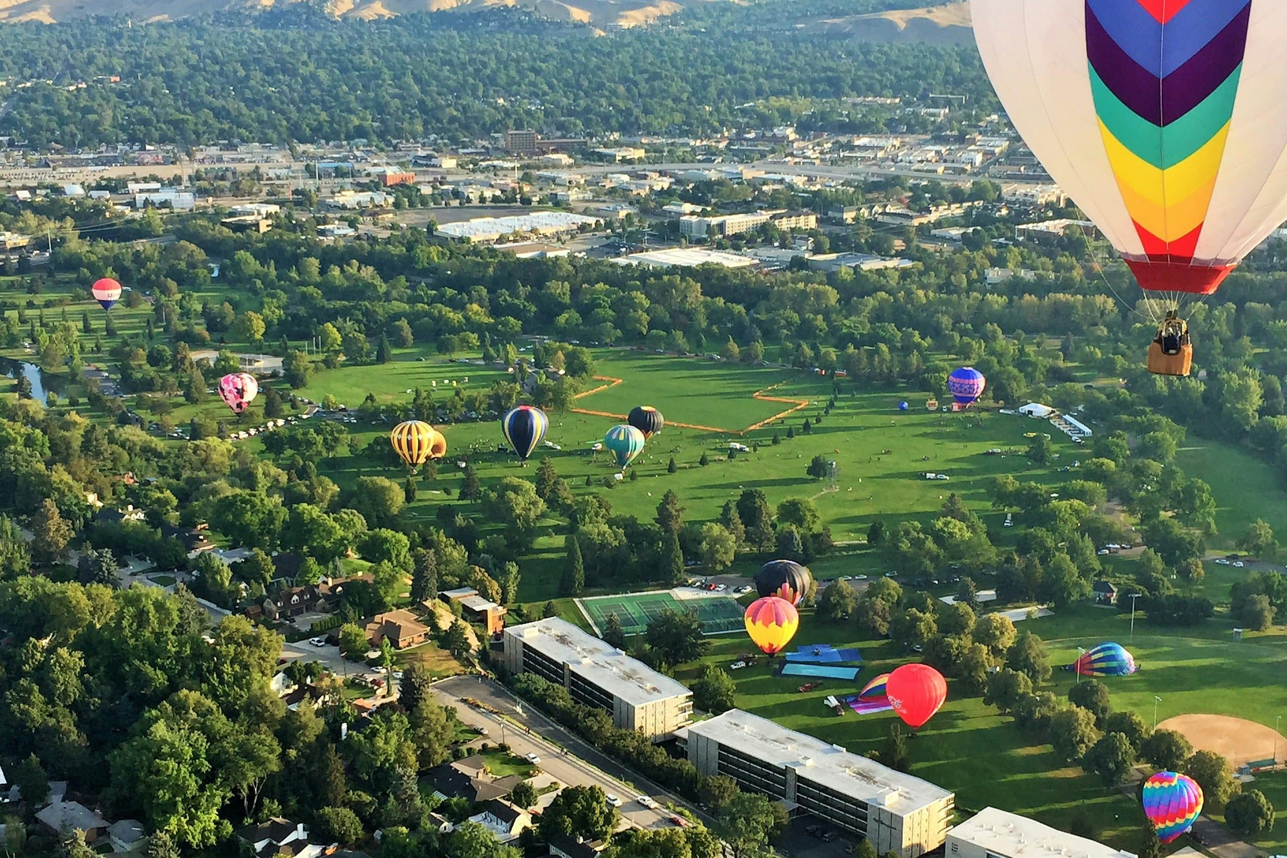 Aerial view of Greater Boise Idaho with hot air balloons over green neighborhoods and the Treasure Valley foothills