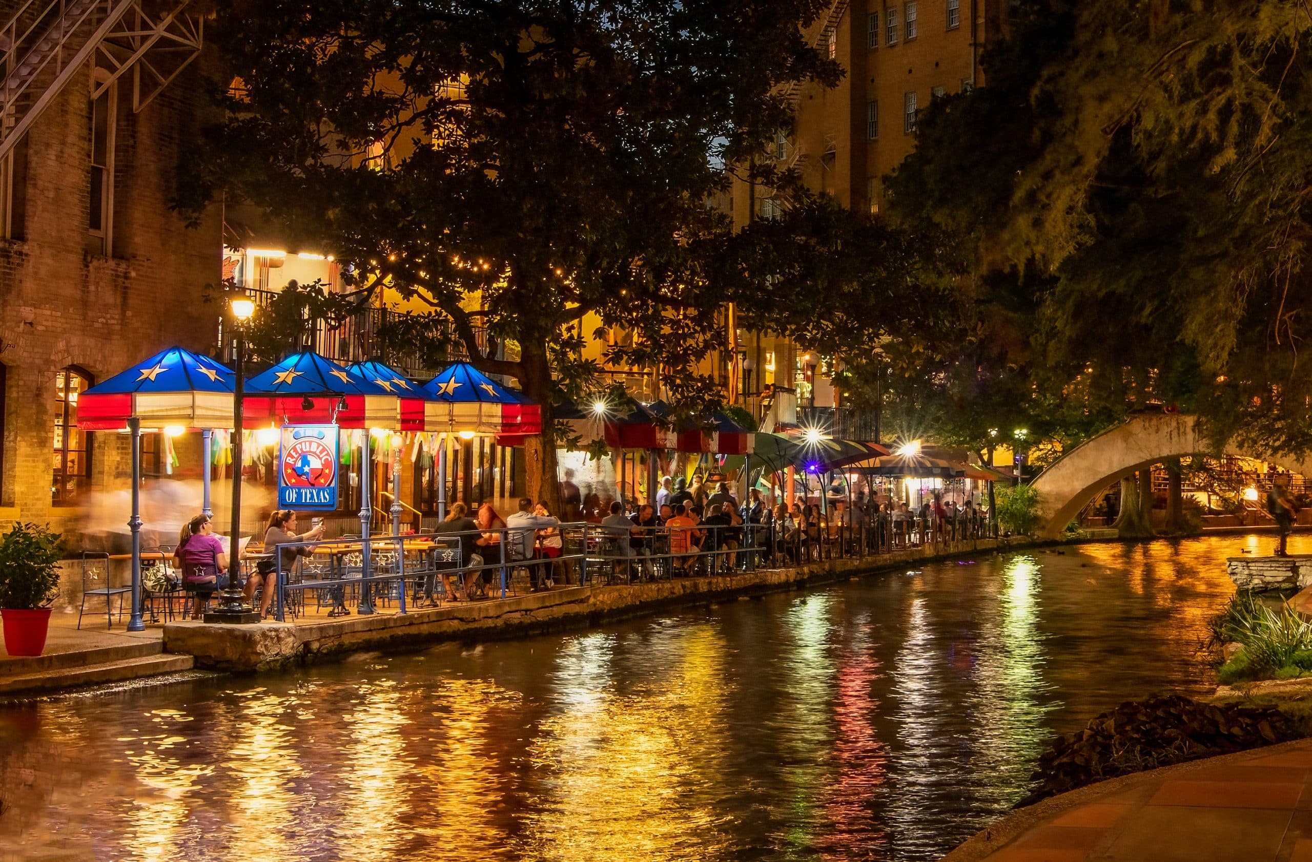 Restaurants and colorful lights reflecting on the San Antonio River Walk at night
